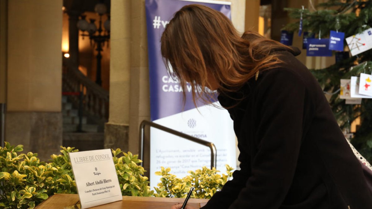 Una dona signa al Llibre de Condol que hi ha a l'entrada a l'edifici de l'Ajuntament.