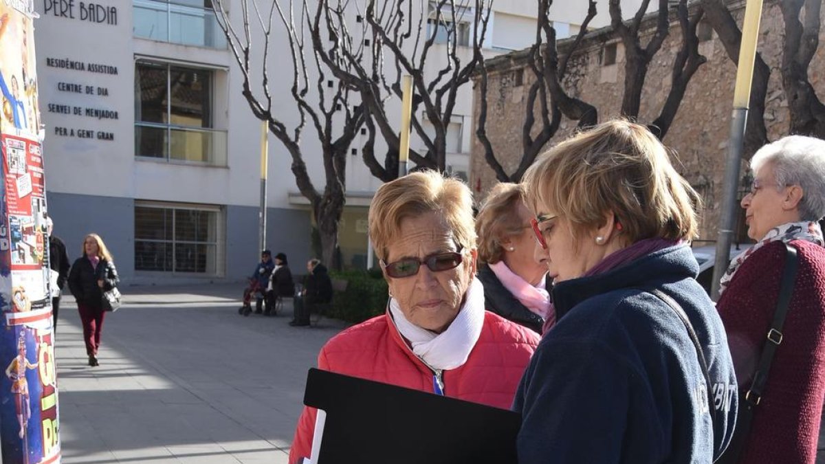 Una agente cívica ofrece información a una mujer que pasea con su perro.