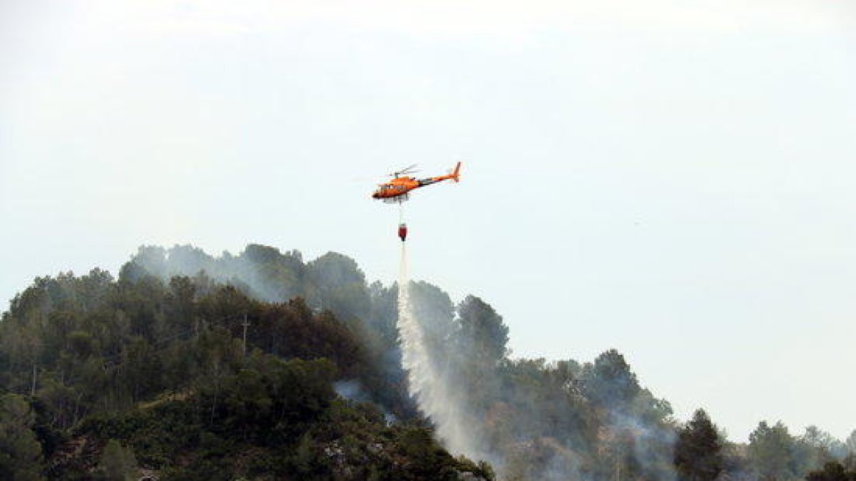 Pla general d'un helicòpter dels Bombers descarregant aigua en un incendi que s'ha originat a Picamoixons, a l'Alt Camp, el 30 de maig del 2017.