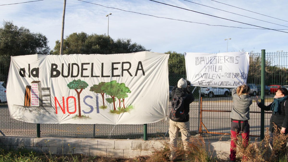 Uns veïns van penjar una pancarta en contra del Pla Parcial Urbanístic de la Budellera, abans de fer una marxa reivindicativa.