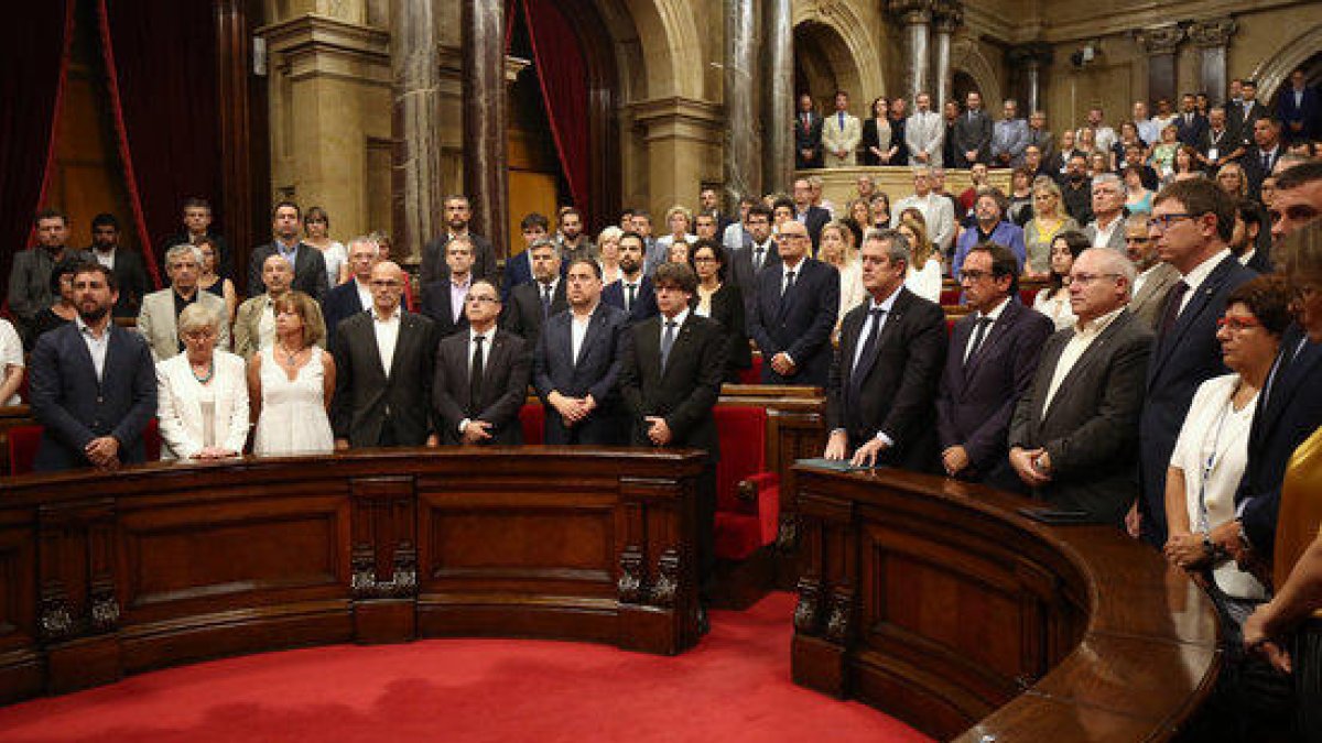 Plano medio de los miembros del Gobierno en el hemiciclo del Parlamento en el minuto de silencio después de leer la declaración de condena de los atentados.