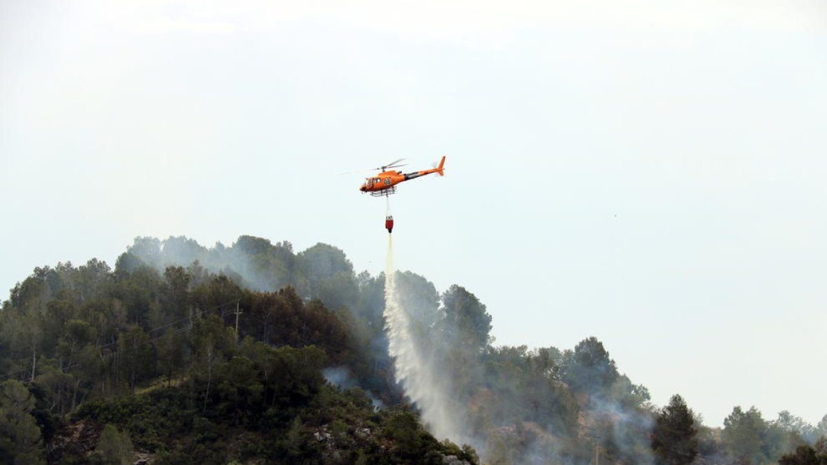 Pla general d'un helicòpter dels Bombers descarregant aigua en un incendi que s'ha originat a Picamoixons, a l'Alt Camp, el 30 de maig del 2017