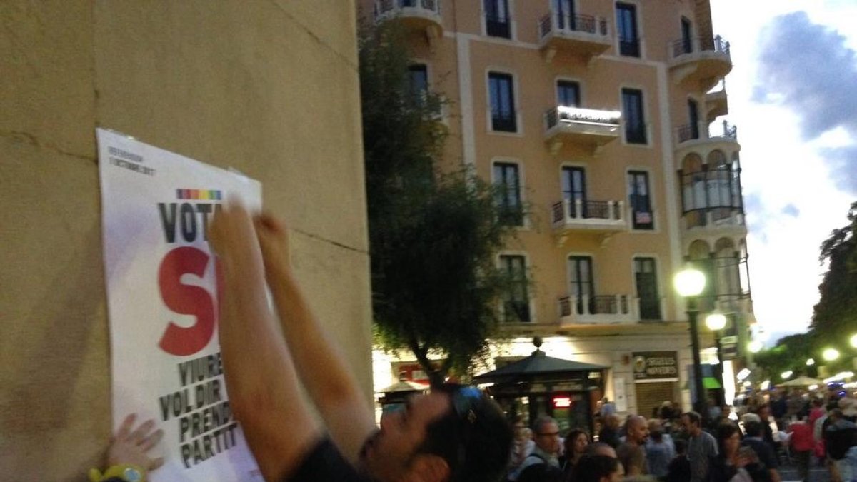 Un participant a l'enganxada col·locant un dels cartells favorables al Sí.