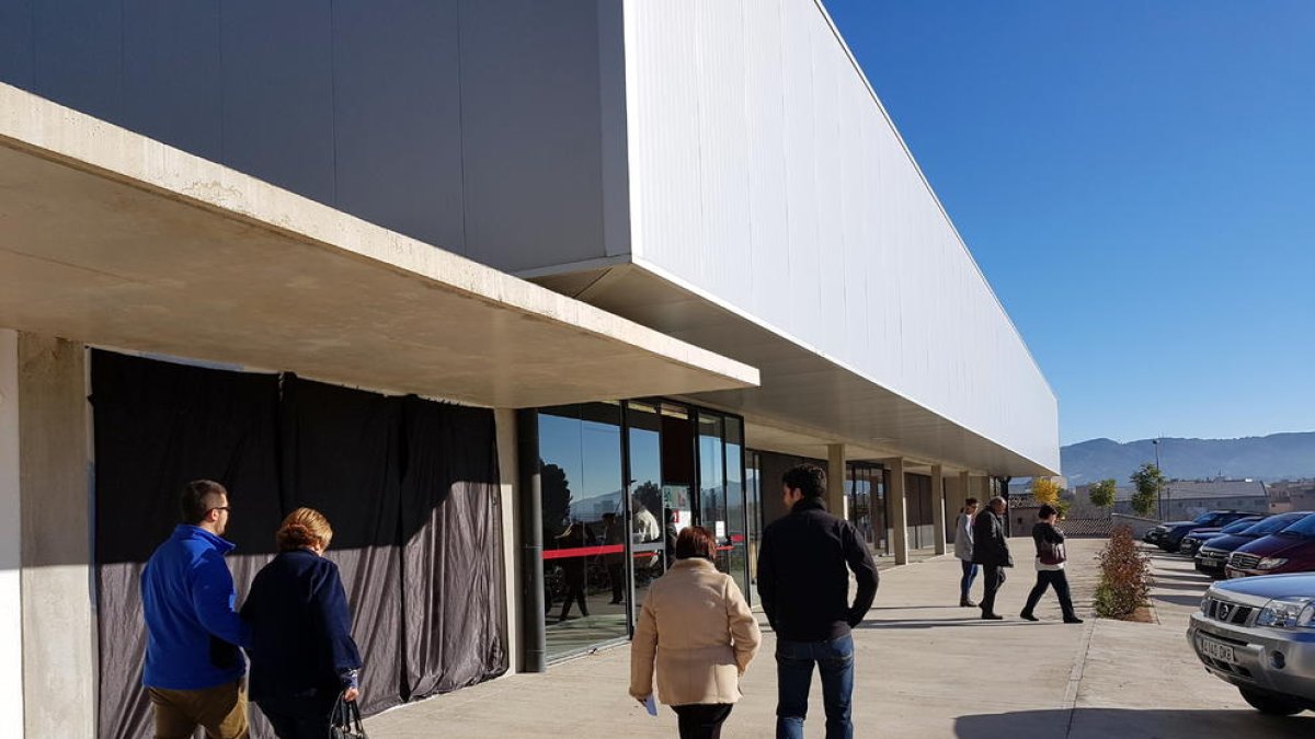 Pla general de l'entrada al pavelló de Roquetes aquest 21-D al matí amb els votants passant per davant del mural d'Ignasi Blanch tapat amb plàstics negres.