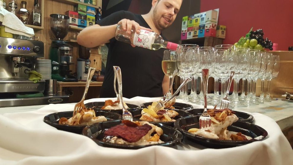 Un restaurador sirviendo copas de vino durante la ruta de tapas.