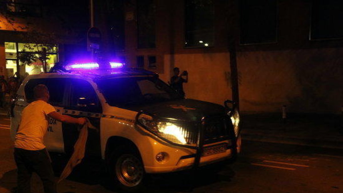 Imagen de un coche de la Guardia Civil increpado por un manifestante y llegando a la Comandancia de Guardia Civil de Travessera de Gracia