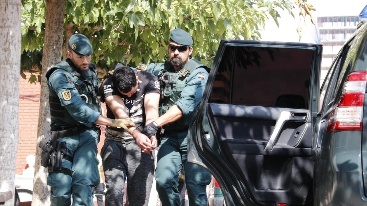 Imatge del noi detingut a Vinaròs, presumptament relacionat amb els atemptats de Barcelona i Cambrils, mentre el traslladen dos agents de la Guàrdia Civil al vehicle policial.