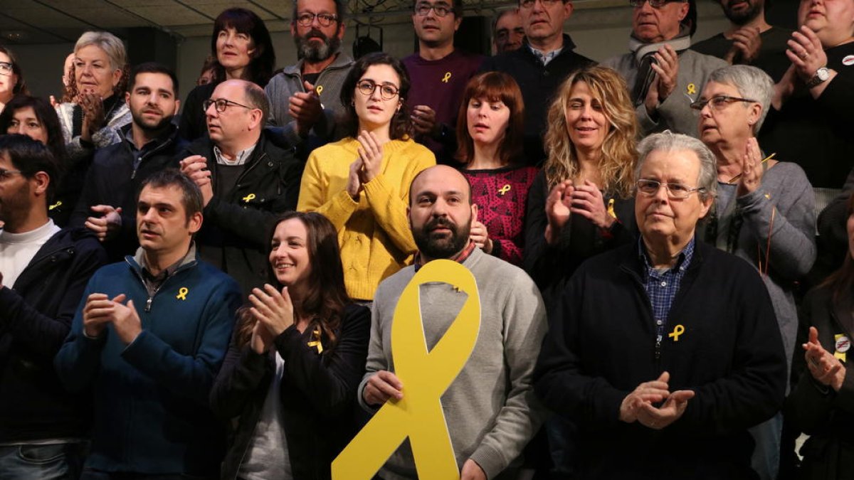 El vicepresident d'Òmnium Cultural, Marcel Mauri, al centre de la imatge subjectant un gran llaç groc acompanyat de membres de l'entitat, a Barcelona.