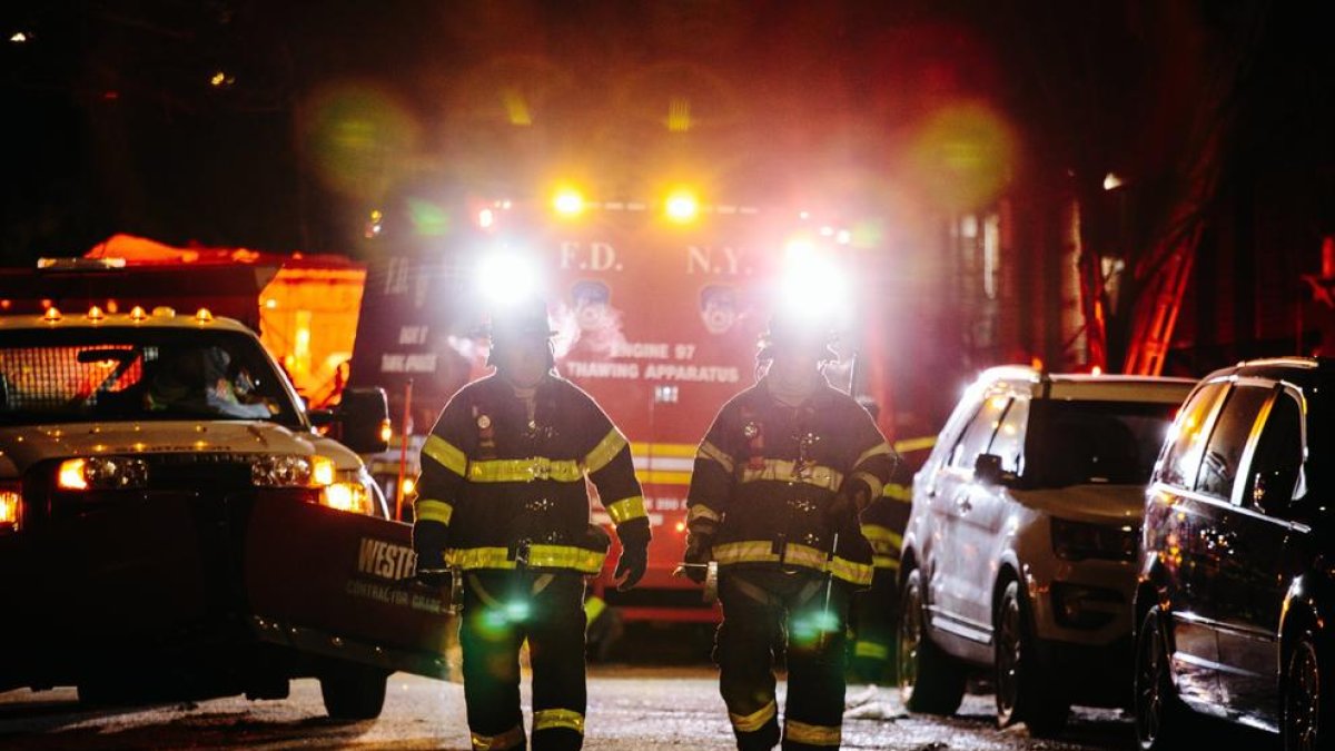 Dos bomberos delante del edificio donde tuvo lugar el incendio.