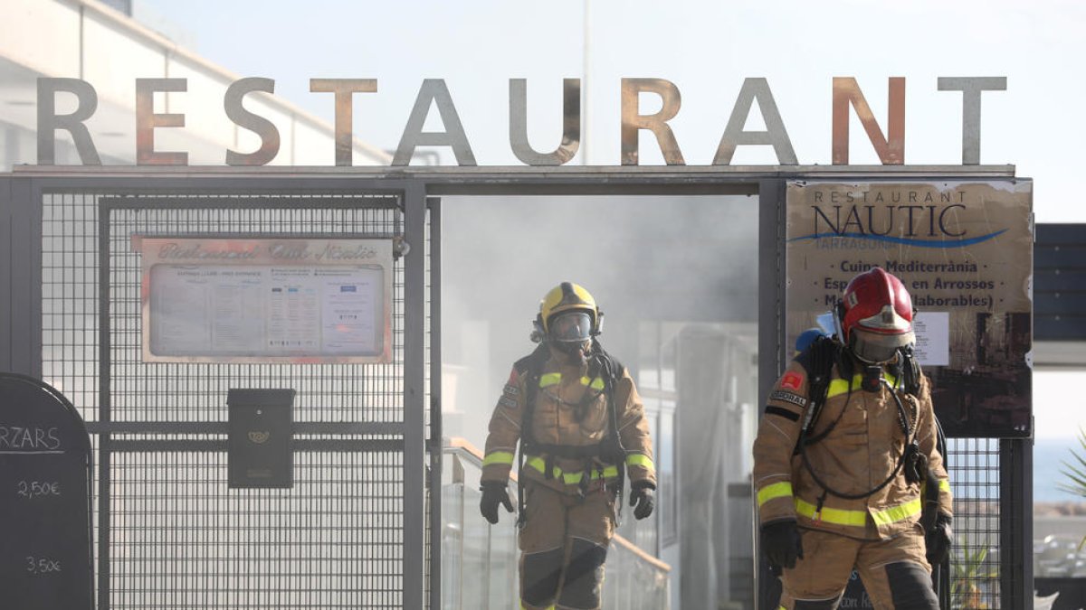 Dos bomberos salen de las instalaciones del Náutico rodeados del humo provocado por el incendio.