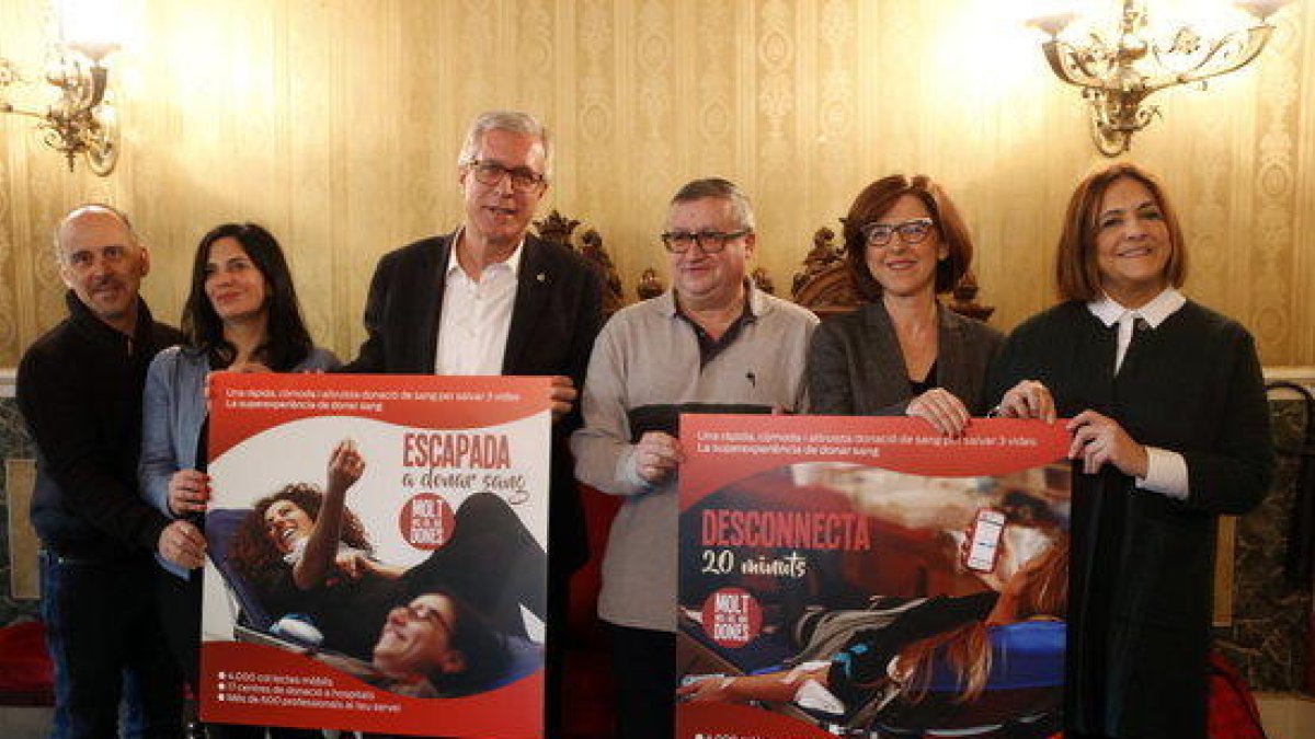 Plano abierto del alcalde Ballesteros y del resto de asistentes a la presentación del Maratón de Donantes de Sangre, en Tarragona, sosteniendo carteles de la campaña de este año.