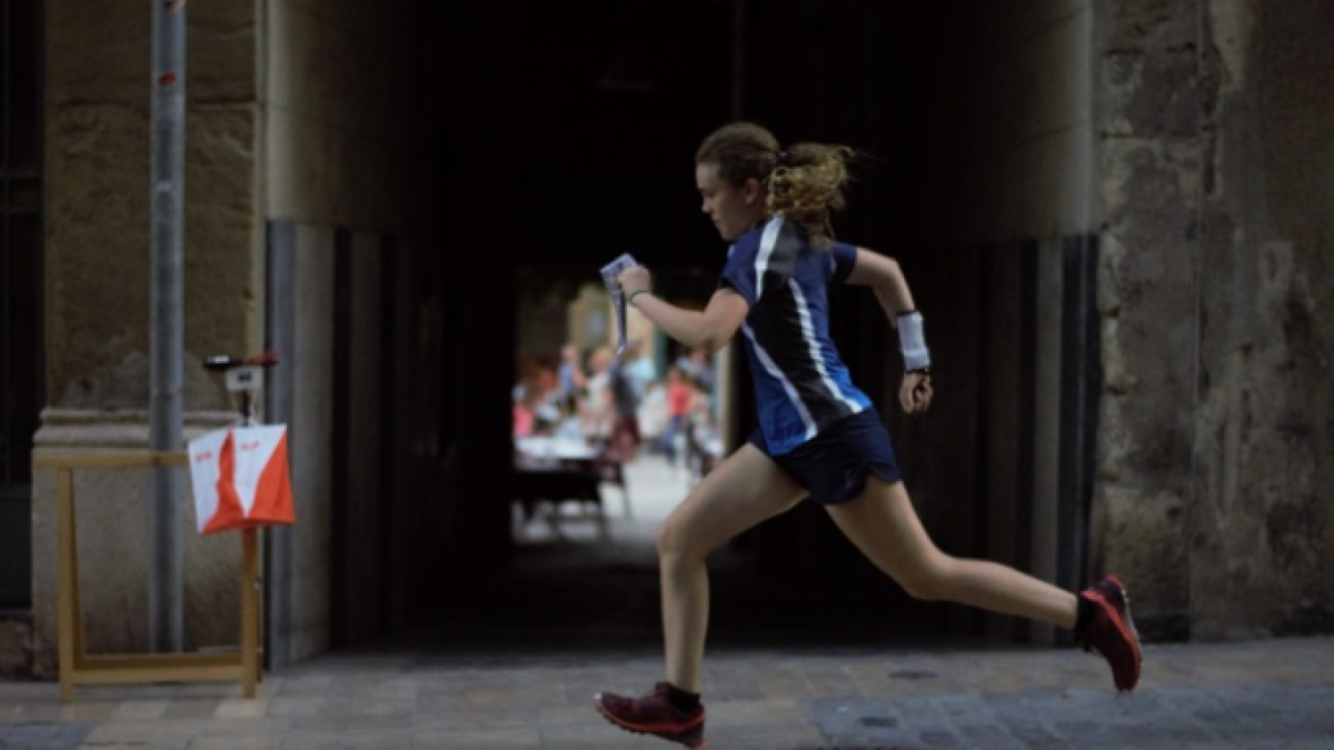 Chica practicando el deporte de l'orientació en la ciudad.