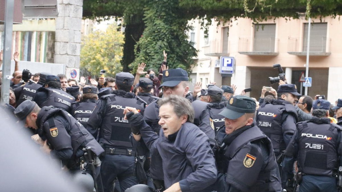 Dos policías se llevan a un hombre de la Escuela Bruguera de Girona.