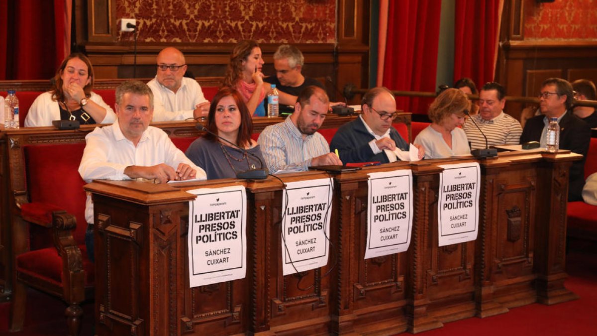 Los concejales de ERC han enganchado cuatro carteles pidiendo 'Libertad presos políticos' ante su fila de asientos.