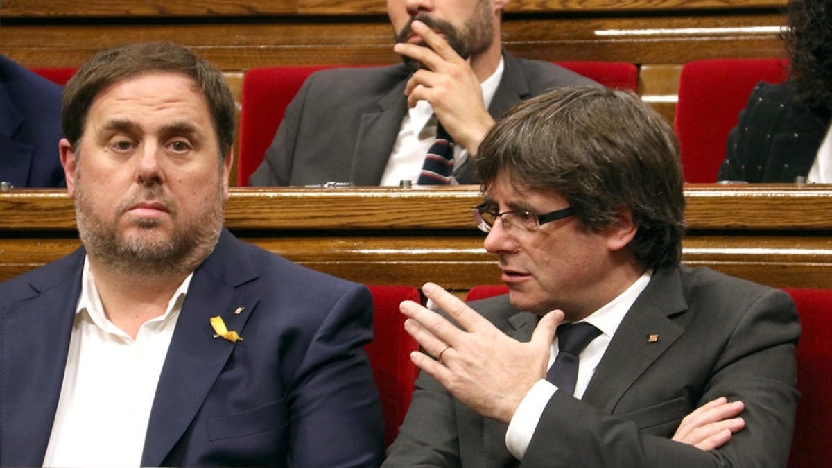 El president de la Generalitat, Carles Puigdemont, parla amb el vicepresident, Oriol Junqueras, al Parlament