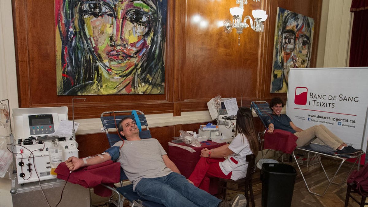 Dos de los donantes de plasma en una sala del Teatro Fortuny, conectados a la máquina de aféresis.