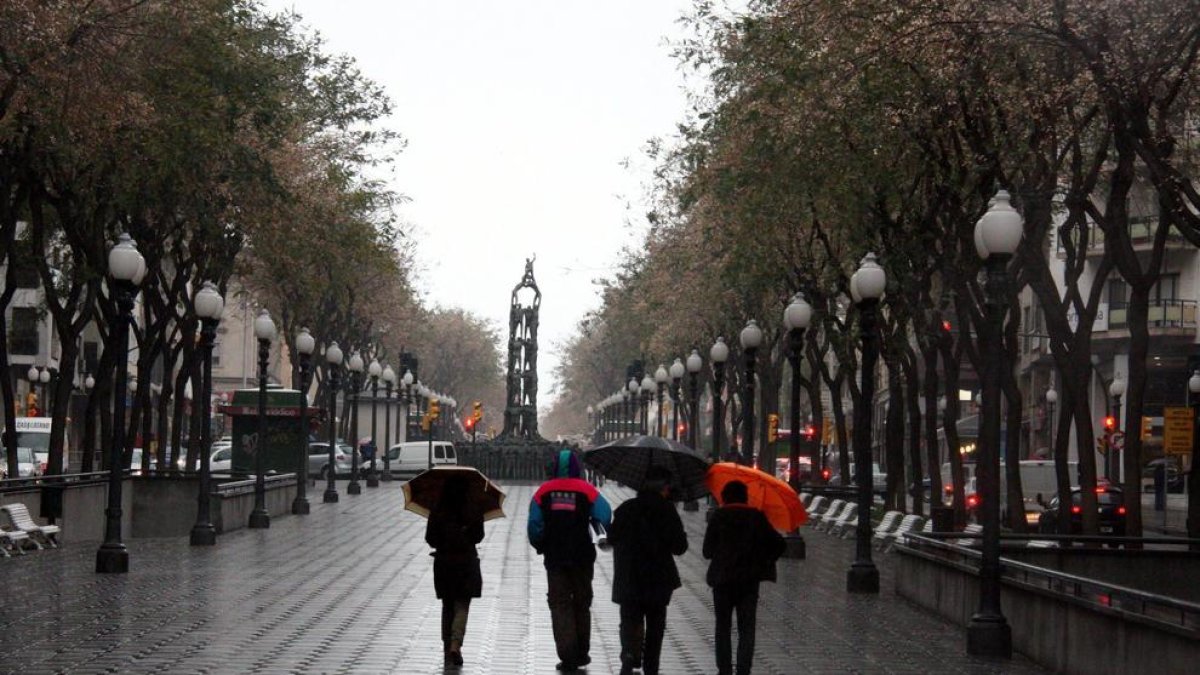 Imatge de diverses persones amb paraigües a la Rambla Nova.