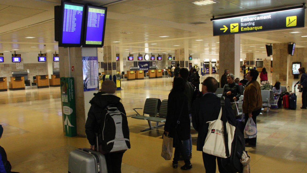 Passatgers fent cua per facturar la seva maleta al mostrador de Ryanair, abans d'agafar un dels vols que la companyia de baix cost irlandesa opera des de l'aeroport de Girona