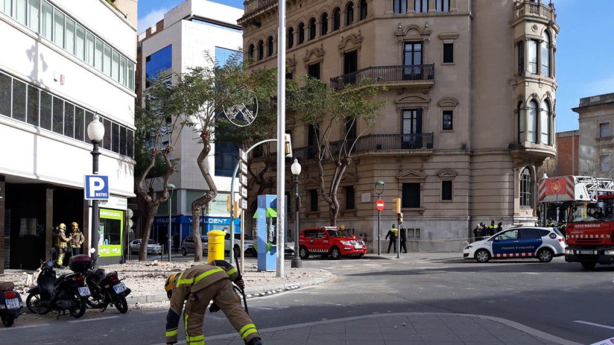 Un bomber recull restes de la terrassa que van quedar al mig del carrer després del despreniment d'ahir al matí.