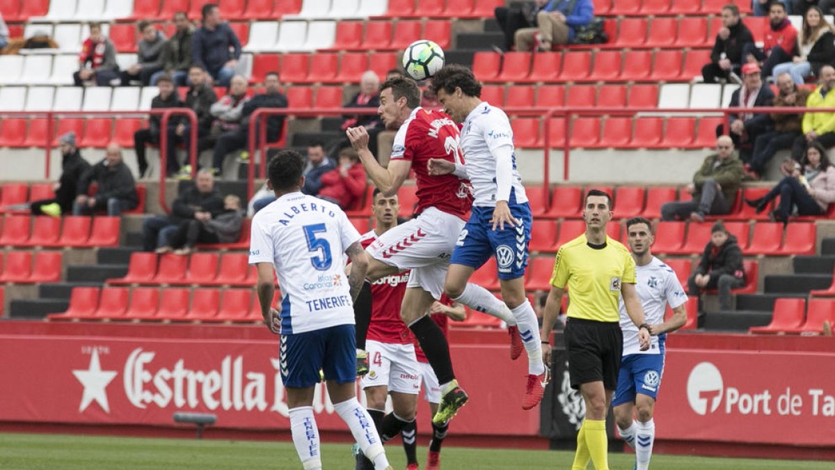 Manu Barreiro salta amb dos rivals durant el partit.