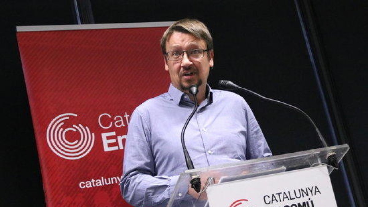 El jefe de filas de los comunes en el Parlament, Xavier Domènech, con el logo del partido de fondo.