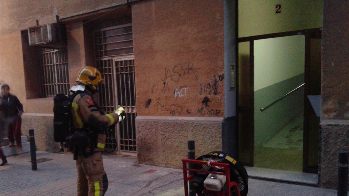 Un bomber, amb un ventilador a la porta de l'immoble.