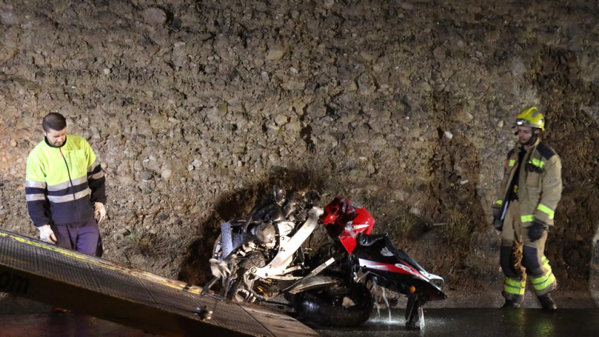 Els serveis d'emergències retiren la moto que ha quedat destrossada després de l'impacte