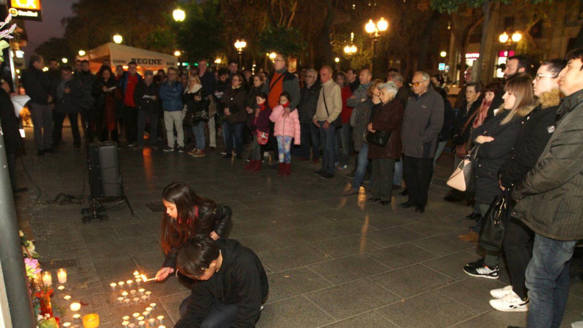 Un nen i una nena encenen espelmes al lloc on la Carolina va morir el passat 9 de febrer.