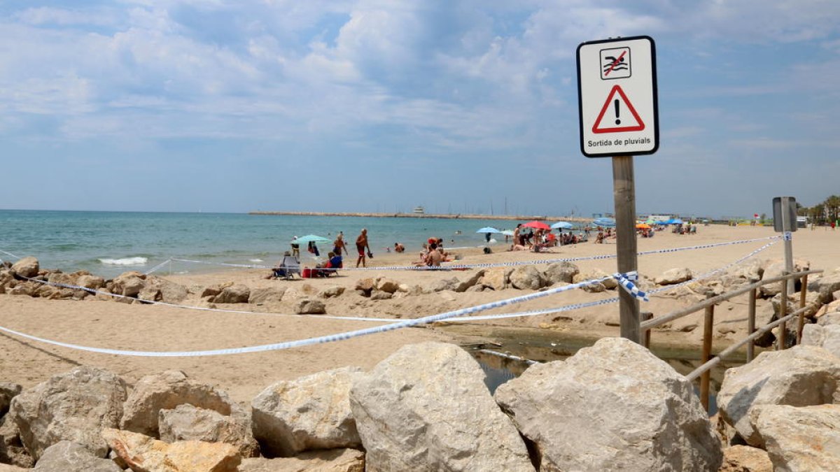Imatge de la platja de Segur de Calafell amb una cinta policial que delimita el perímetre per un vessament fecal.