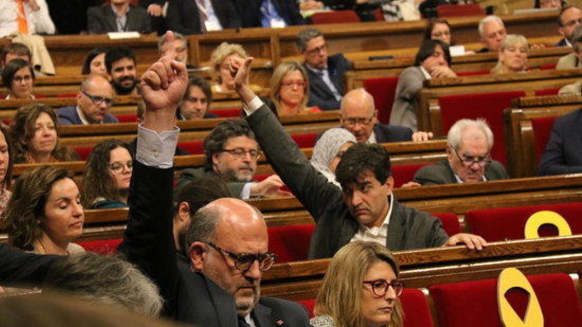 El portaveu adjunt de JxCat Eduard Pujol i el president d'ERC, Sergi Sabrià, marquen el sentit del vot durant el debat de la reforma de la llei de Presidència al Parlament.