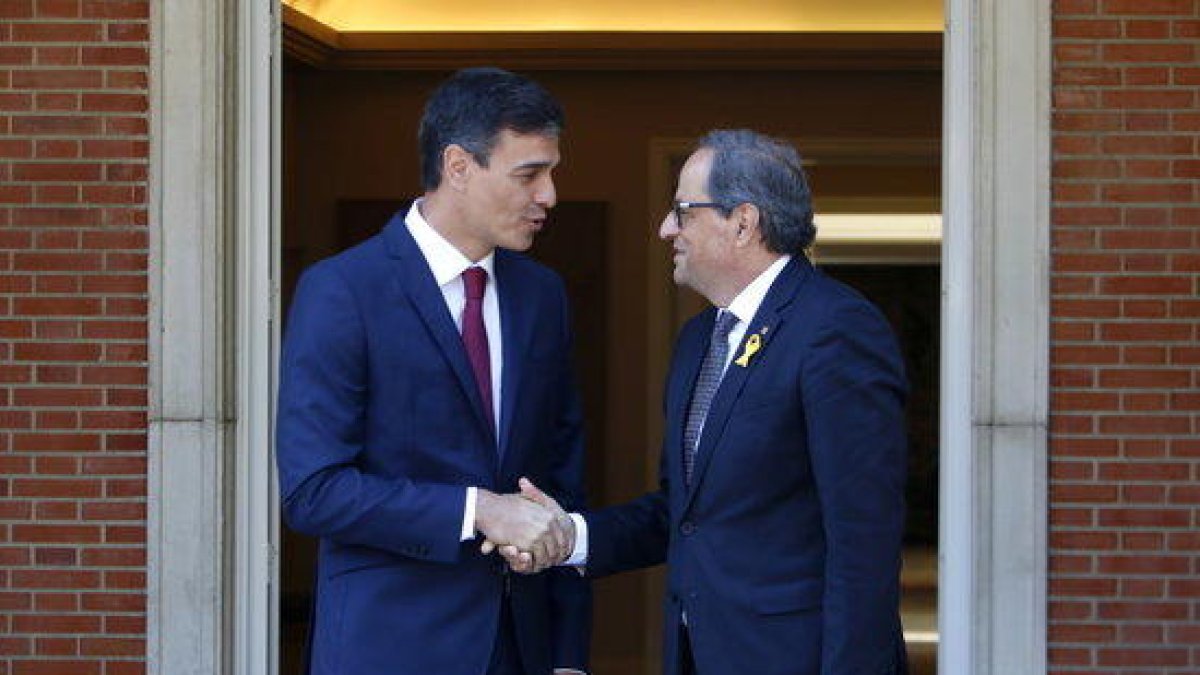 El presidente de la Generalitat, Quim Torra, y el presidente del gobierno español, Pedro Sánchez, encajan las manos en las puertas del palacio de la Moncloa.