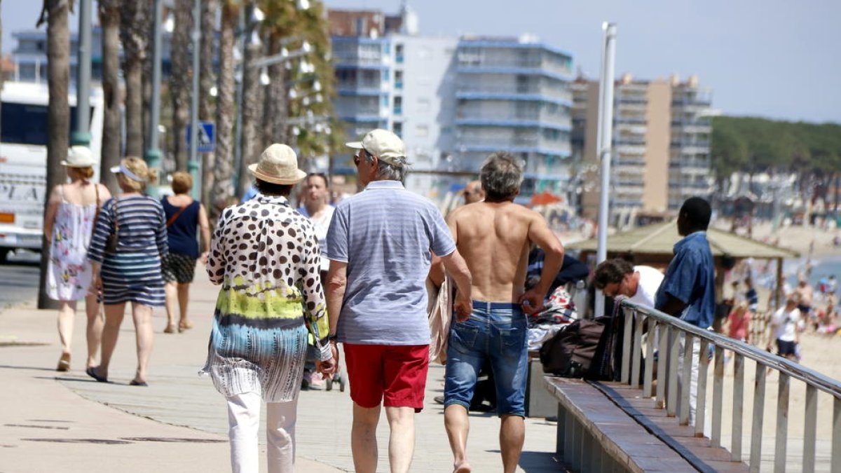 Plan general de varios turistas paseando por el paseo marítimo de la playa de la Pineda, en Vila-seca, el 9 de mayo del 2018