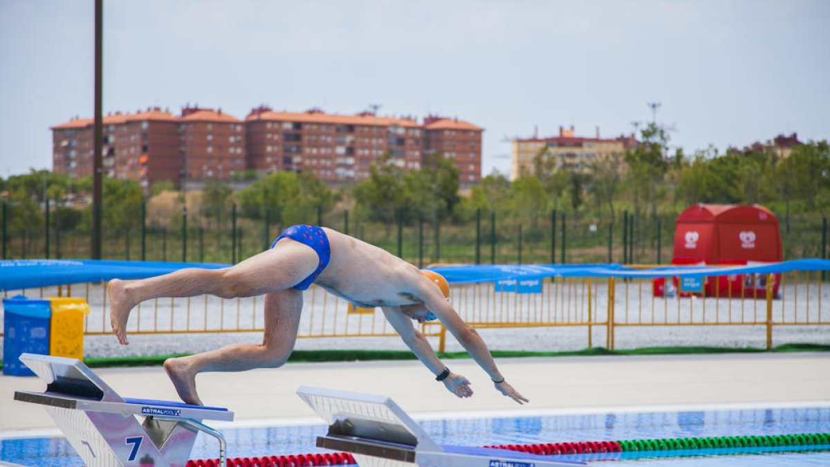 Un nedador es llença a la piscina, ja sense la grada mòbil que hi va haver durant els Jocs i que permet veure, al fons, Campclar.