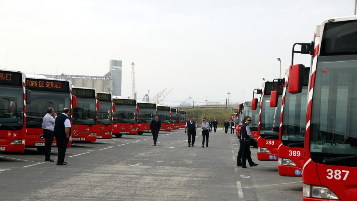 Plano abierto de decenas de autobuses en cocheras, con varios trabajadores del EMT de Tarragona delante, en el primer paro parcial de la huelga.