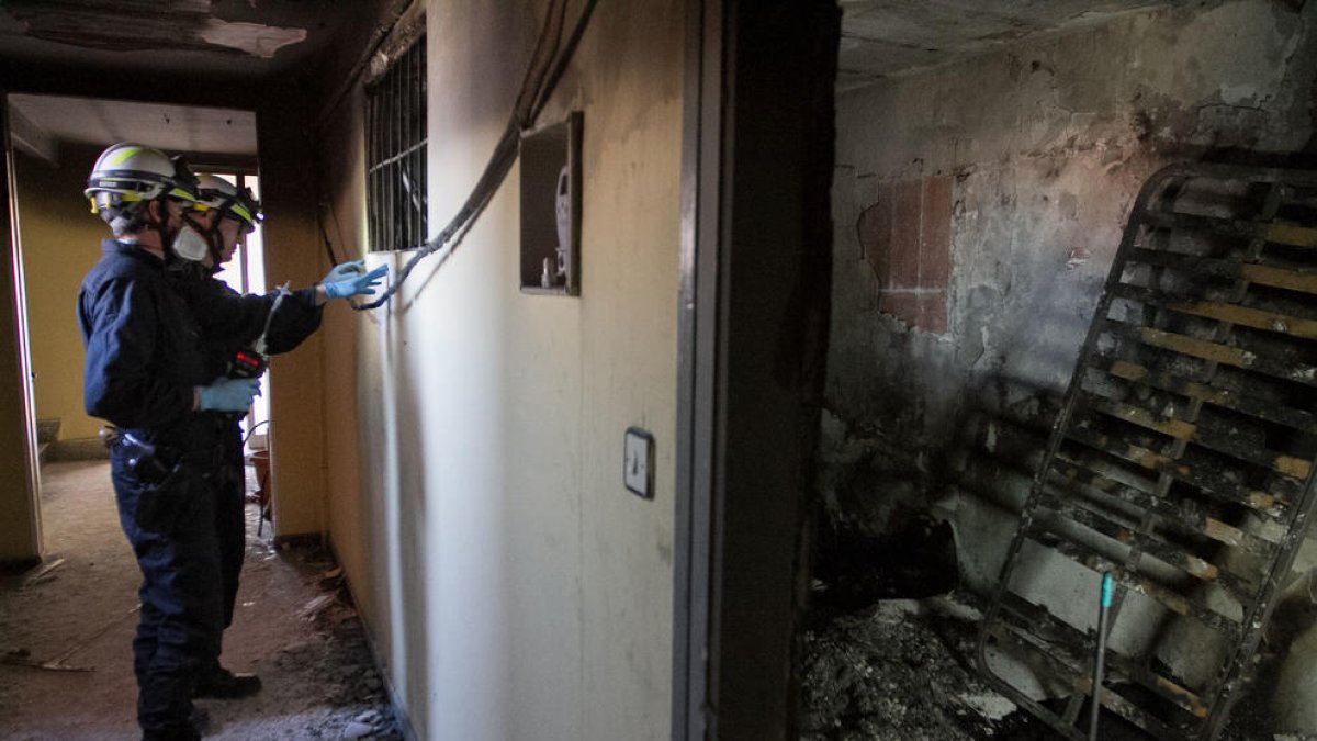 El interior del piso de la vivienda incendiada en Reus, con técnicos revisándolo.