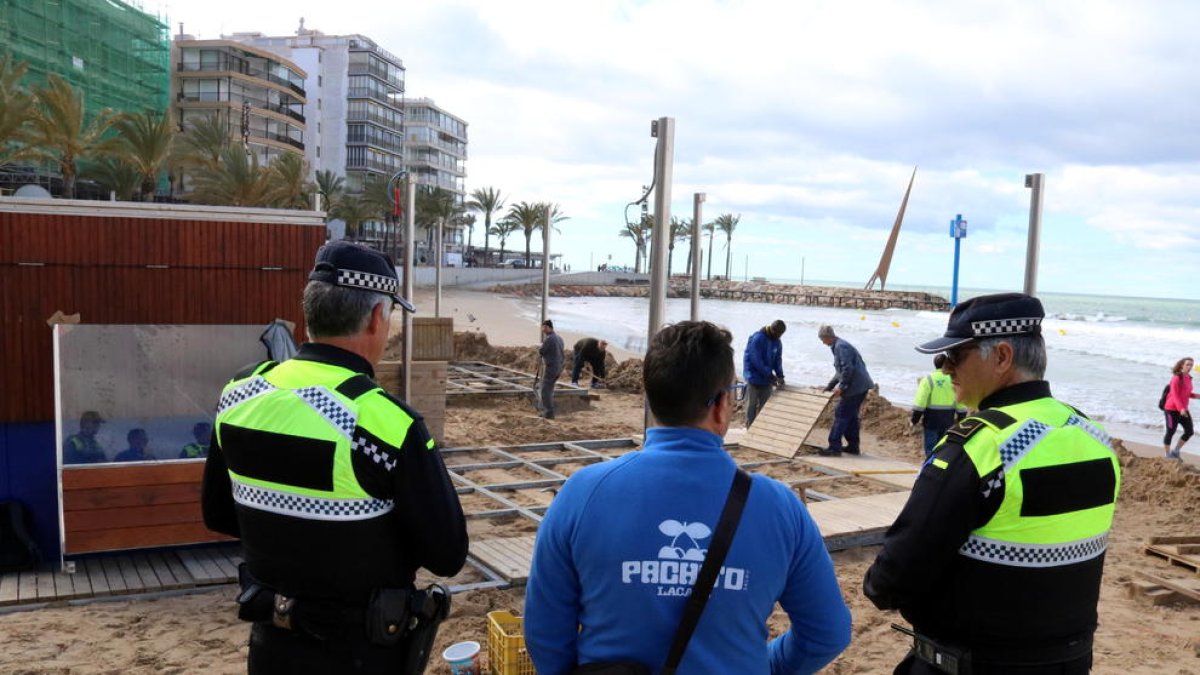 Agents de la Guàrdia Urbana de Salou, parlant amb el propietari d'una guingueta dels danys que ha patit la terrassa a causa del temporal, en un extrem de la platja de Llevant.