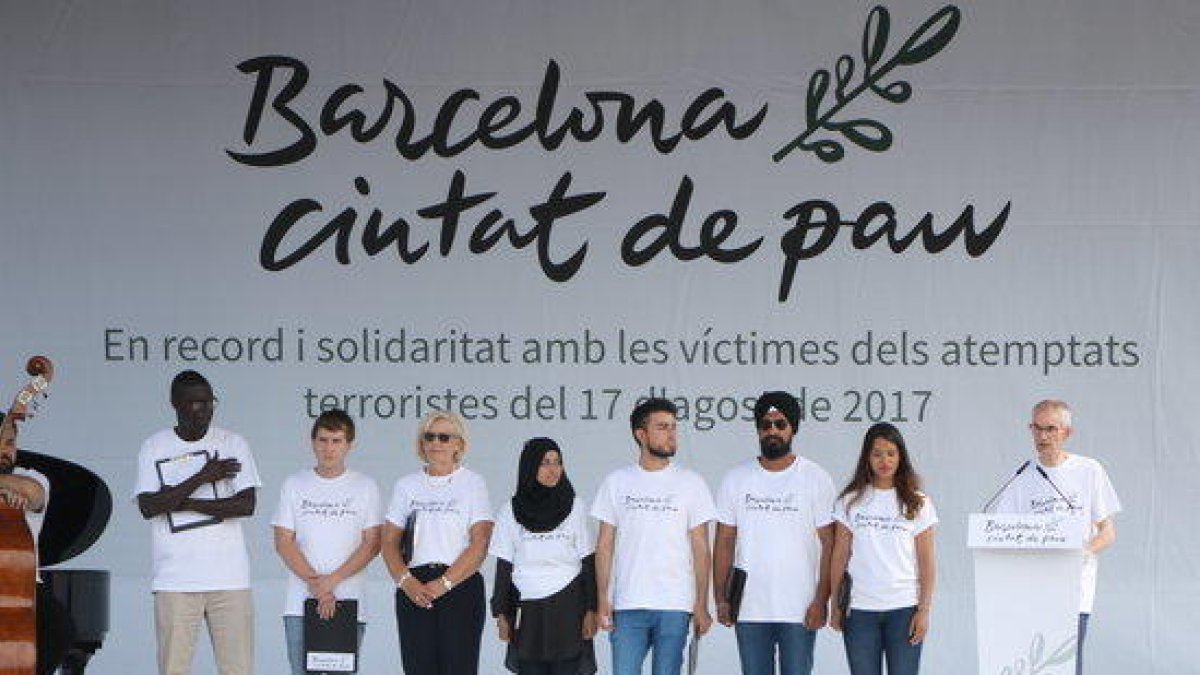 Plano general del escenario de plaza Catalunya donde hay las ocho personas encargadas de leer el manifiesto en recuerdo de las víctimas del 17-A.