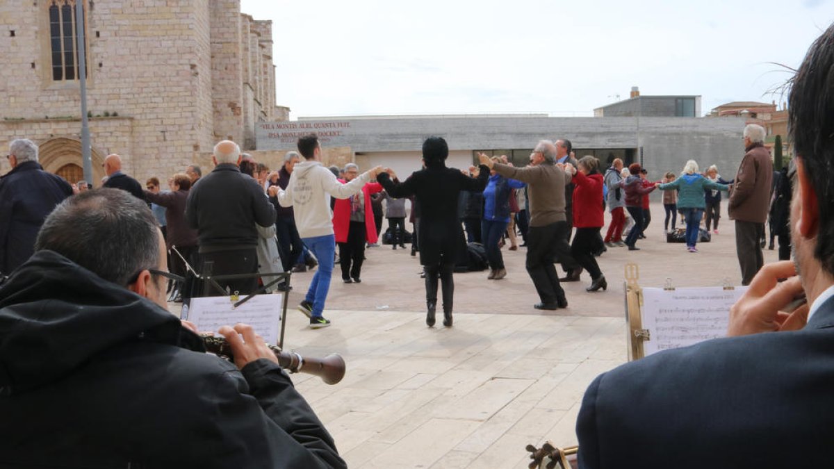 Diverses persones ballant sardana a Montblanc i dos músics de la cobla.