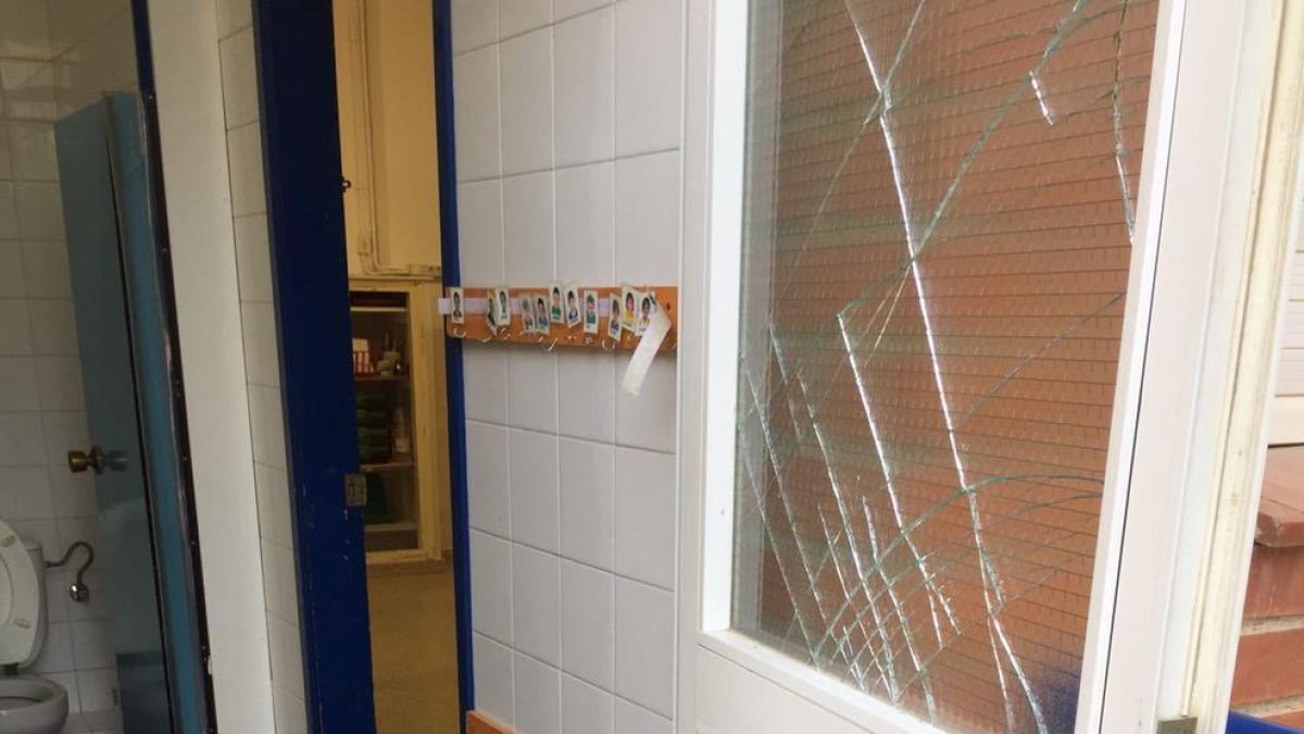 Imatge d'una de les portes amb els vidres trencats a l'Escola Cèsar August.
