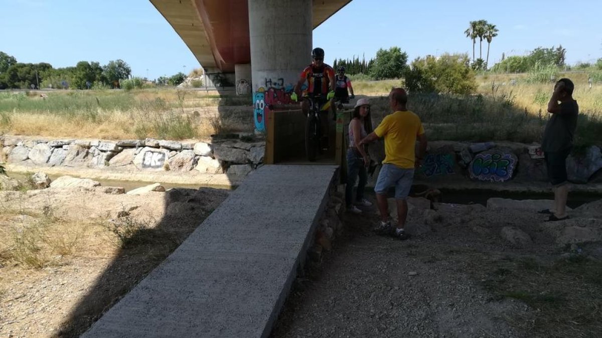 Dos ciclistes creuen el Francolí per la passera.