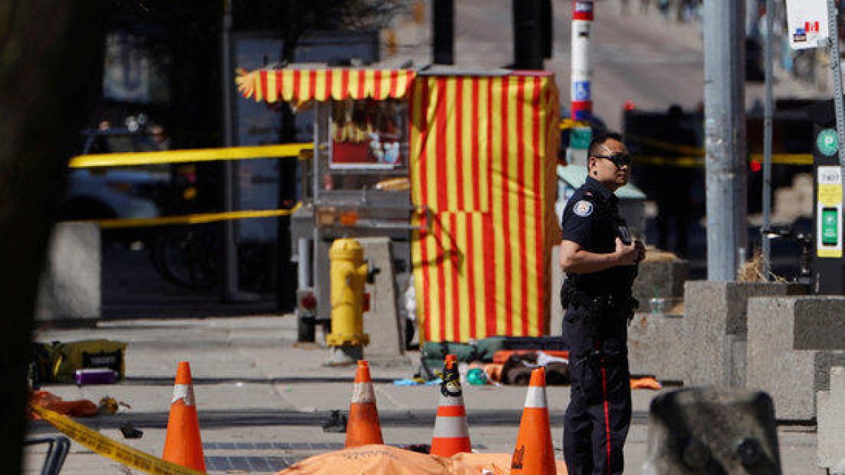 Un agent de policia al costat d'una de les víctimes d'un atropellament múltiple d'una furgoneta a Toronto, al Canadà.