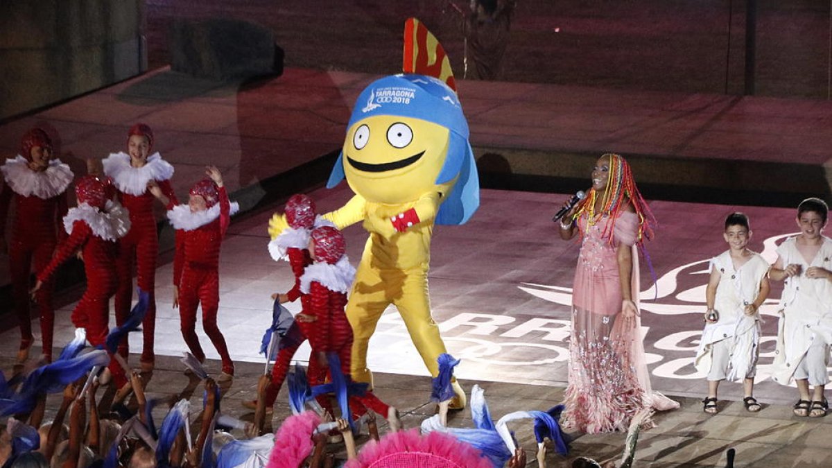 Plano general de la mascota de los Juegos del Mediterrani Tarragona 2018 bailando al espectáculo final de la ceremonia inaugural con la cantante Lucrecia.