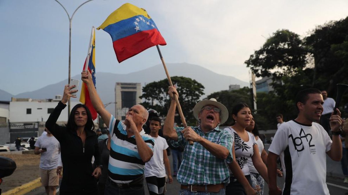 Simpatizantes del presidente interino Juan Guaidó hacen ondear banderas este martes en la base militar La Carlota.