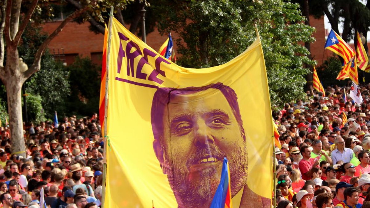 Una pancarta que porta escrit 'Free' amb la cara d'Oriol Junqueras alçada al mig de la manifestació de la diada convocada per l'ANC.