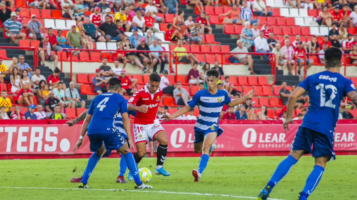 Pol Ballesteros, envoltat de rivals durant el Nàstic-Llagostera