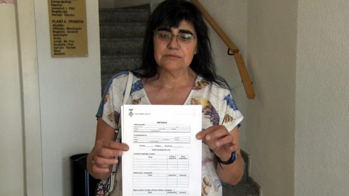 Maria Rosa Piñol con el formulario de daños que reparte el Ayuntamiento de Flix para inventariar los desperfectos del fuego.