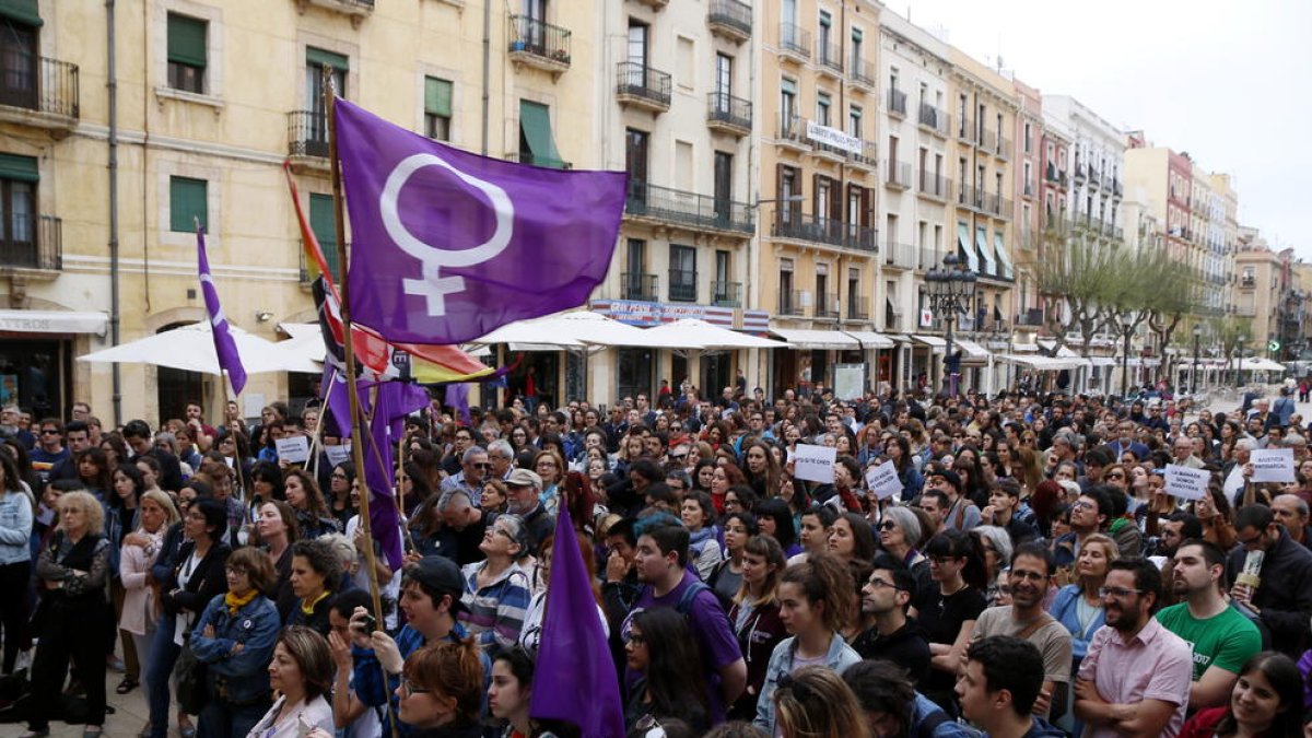 Pla general de les persones concentrades a la plaça de la Font de Tarragona en rebuig a la sentència de 'La Manada', amb una bandera feminista sobresortint d'entre la multitud. Imatge del 26 d'abril del 2018