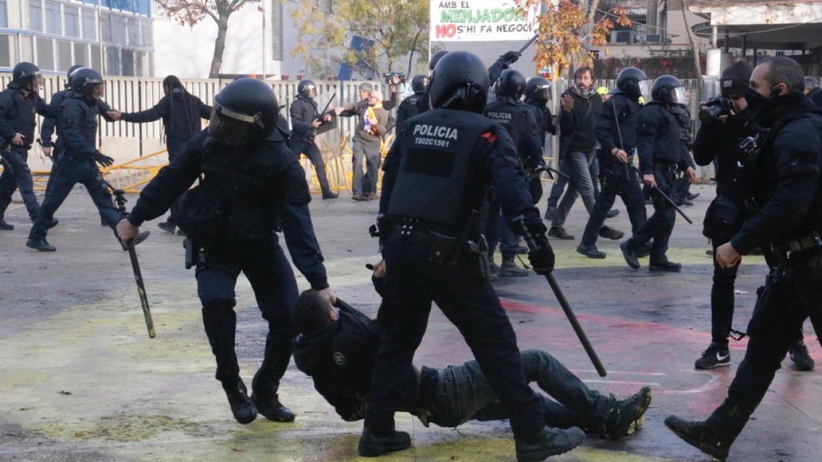 Dos agentes de los Mossos, arrastrando a un manifestante antifascista a la plaza U de Octubre de Gerona.