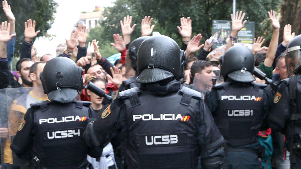 agents de la policia espanyola d'esquenes intentant impedir el pas de ciutadans que feien cua per votar a l'Escola Ramon Llull, l'1 d'octubre de 2017