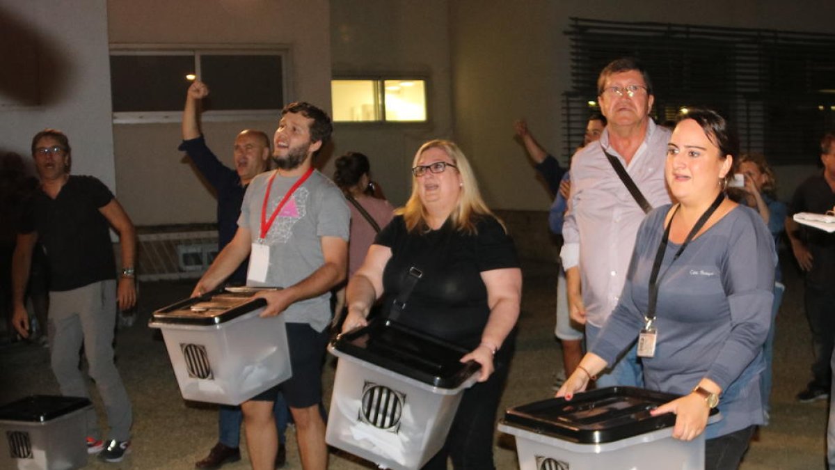 Diverses persones mostren les urnes amb sobres sense papereta un cop acabades les votacions a l'Institut Antoni de Martí i Franquès de Tarragona, l'1 d'octubre del 2017.
